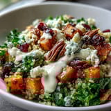 Fluffy quinoa topped with roasted sweet potatoes, massaged kale, cranberries, pecans, and blue cheese in a Harvest Kale Quinoa Bowl drizzled with lemon tahini dressing.