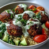 Crisp baked falafel rest on fluffy quinoa in a Falafel Quinoa Salad Bowl, topped with cucumber and cherry tomatoes.