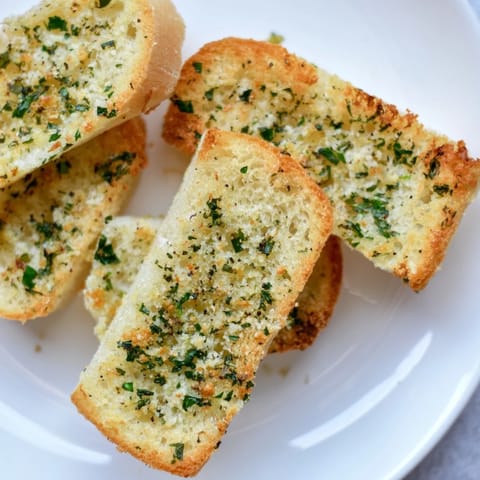 Melted garlic butter coats toasted Garlic Bread, promising a warm, savory bite alongside pasta.