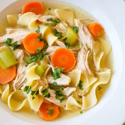 Homemade Chicken Noodle Soup featuring vibrant carrots and celery in a savory broth, ready to enjoy.