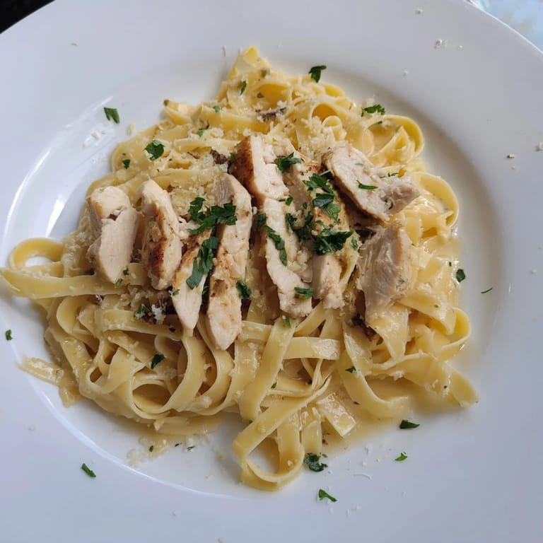 Close-up shot shows steaming, homemade fettuccine Alfredo, a classic creamy pasta dish, ready to eat.