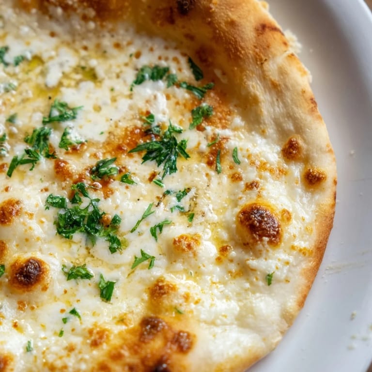 Freshly baked Creamy Garlic White Pizza featuring a velvety garlic cream sauce and a sprinkle of chopped parsley on top.
