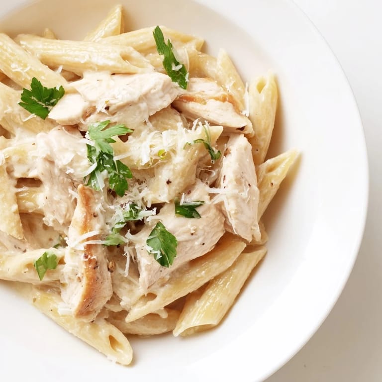Tender penne pasta and sliced roasted chicken tossed in a silky roasted garlic cream sauce, garnished with parsley