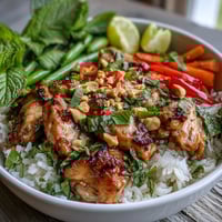 Creamy coconut rice topped with sautéed Thai chicken, crisp bell peppers, and fresh herbs in a vibrant bowl.  