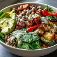 Fork-tender roasted sweet potato and red onion top a bed of fluffy quinoa and black-eyed peas in this vibrant Black-Eyed Pea Buddha Bowl, drizzled with creamy tahini dressing.
