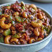 Close-up of a steaming bowl of homemade Black-Eyed Pea Chili, topped with cilantro and sour cream.