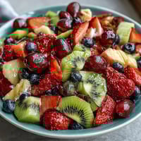 Vibrant spring fruit platter with strawberries, pineapple, and kiwi, served with creamy honey-yogurt dipping sauce for a refreshing appetizer.