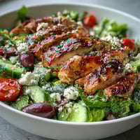 Greek Salad Bowl with Grilled Chicken topped with juicy marinated chicken and creamy feta on crisp romaine.  